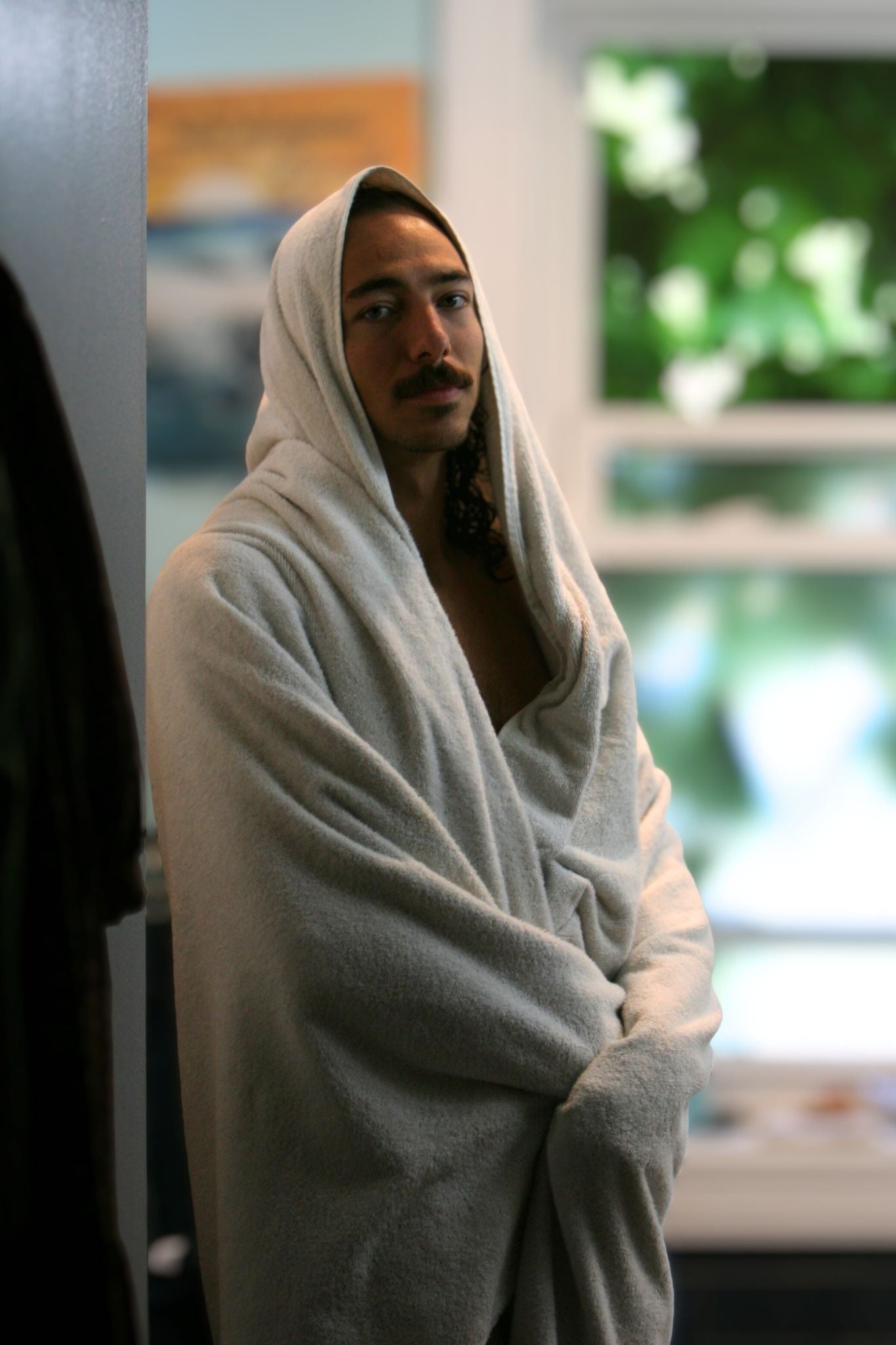 Person wrapped in a giant towel standing in a room with blurred background