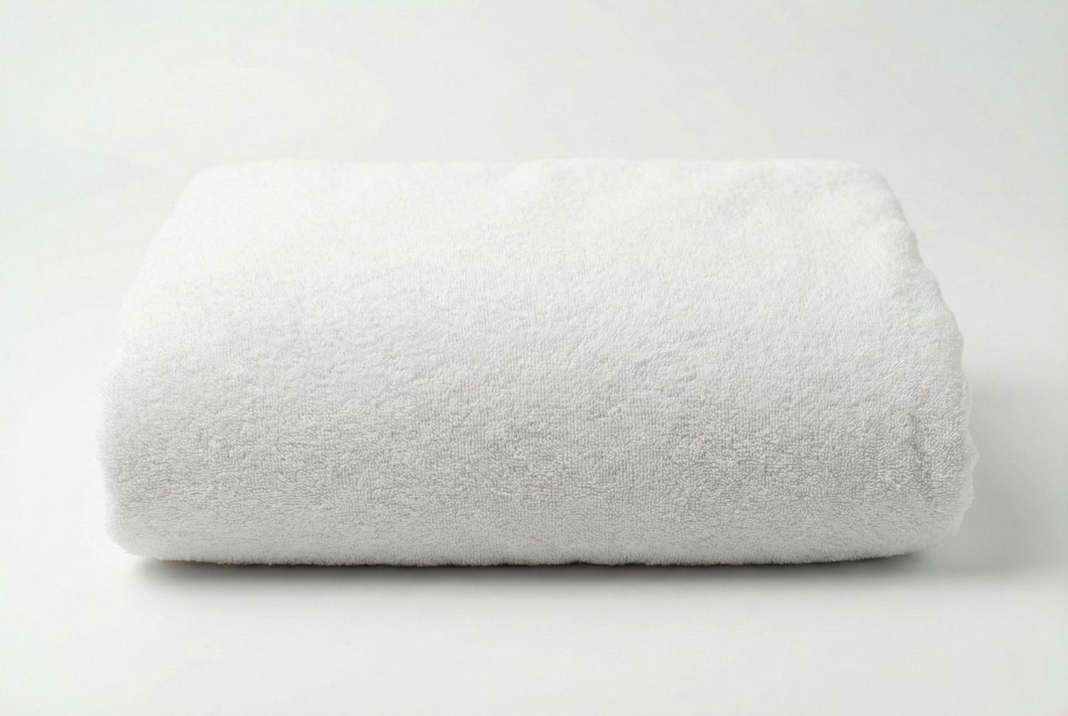 Folded big white Turkish cotton towel on a light gray background