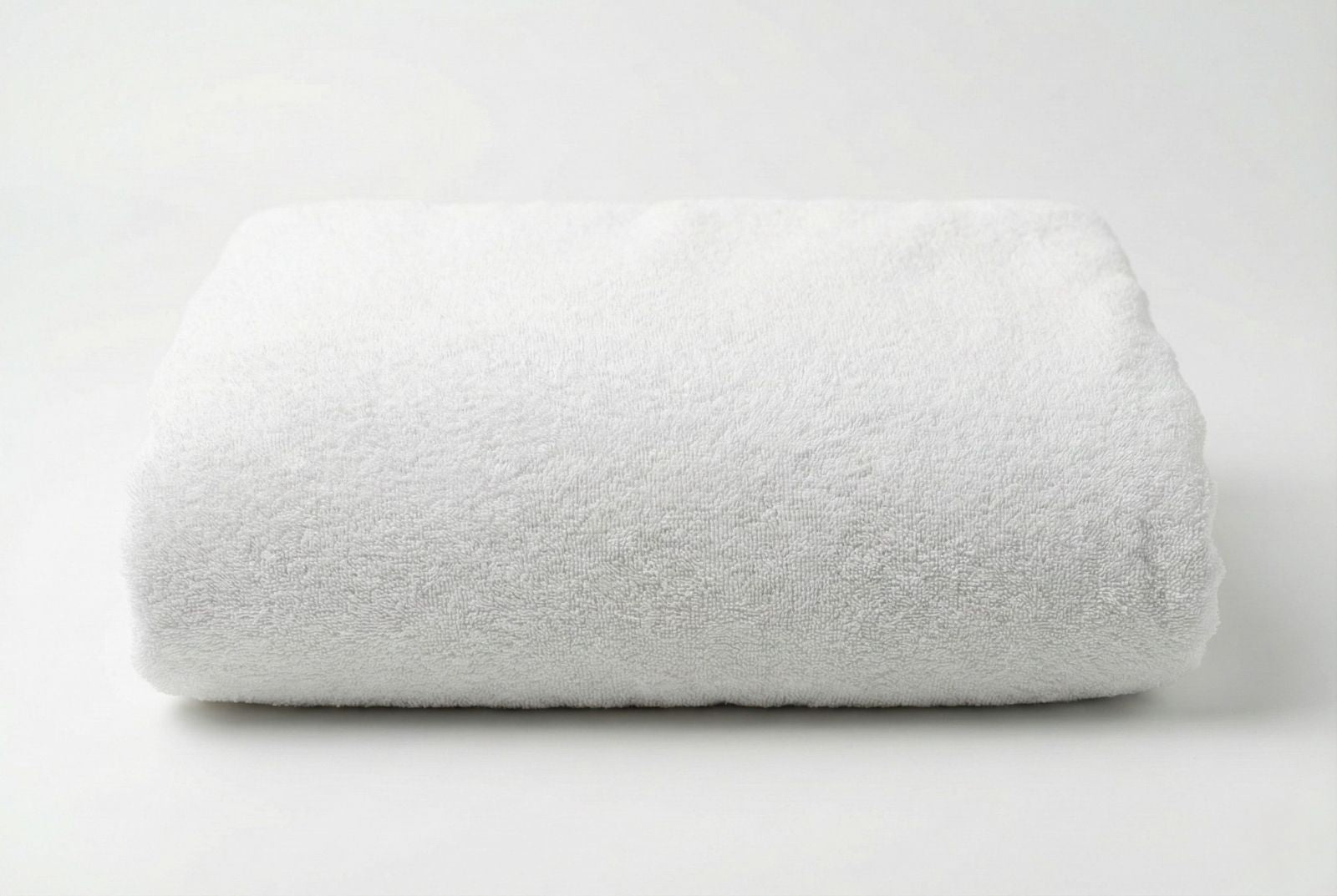 Folded big white Turkish cotton towel on a light gray background