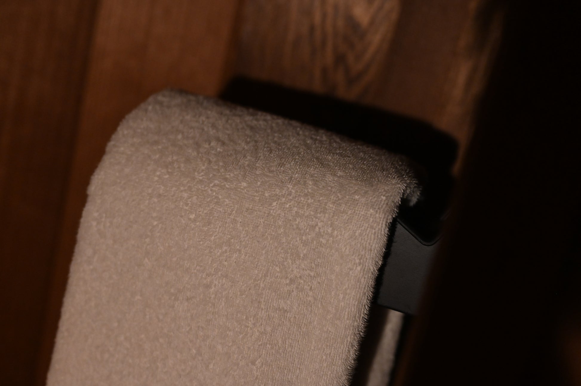 Giant towel on a black towel rack against a wooden wall.