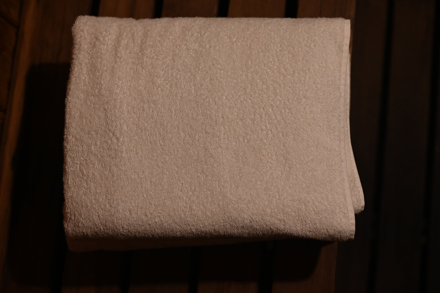 White oversized Turkish cotton towel folded in a sauna against a dark background